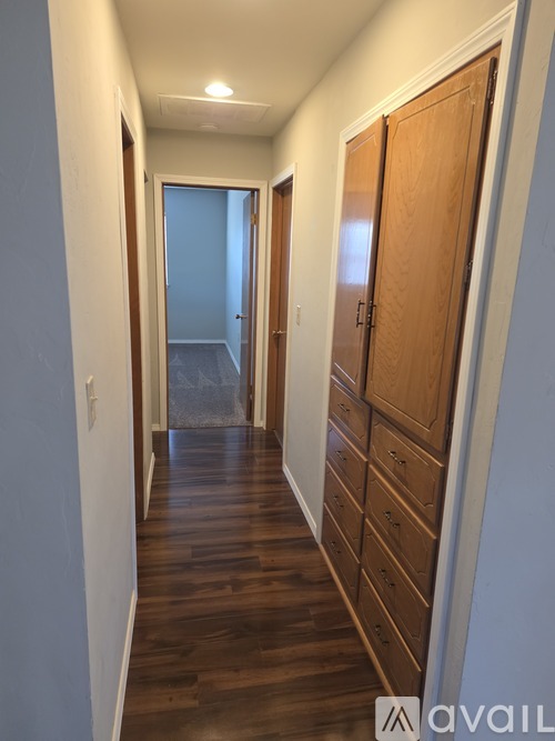 A long hallway with a wooden floor and a white wall on the left.
