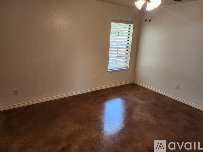 A room with a brown floor and a window with blinds.