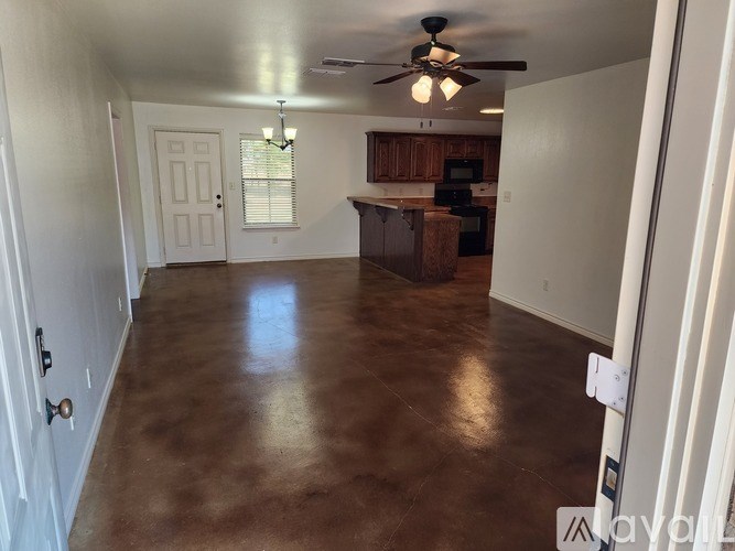 A room with a brown floor and a ceiling fan.