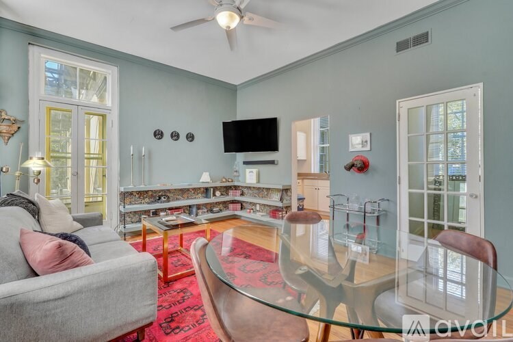 A living room with a grey couch, a glass table, and a television.