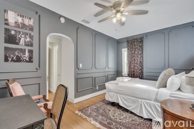 A bedroom with a bed, chair, and pictures on the wall.