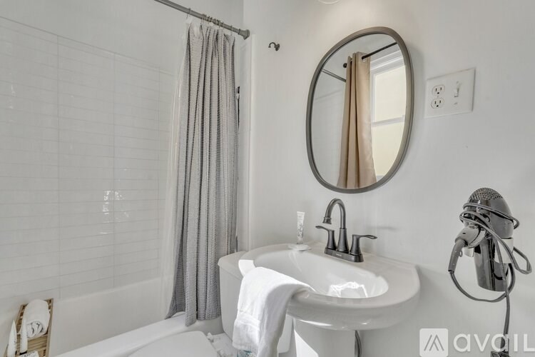 A white sink with a round mirror and a shower curtain.