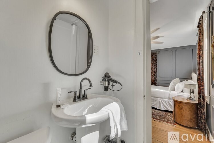 A bathroom with a white sink and a round mirror.