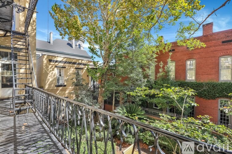 A balcony with a metal railing and a tree in front of a building.