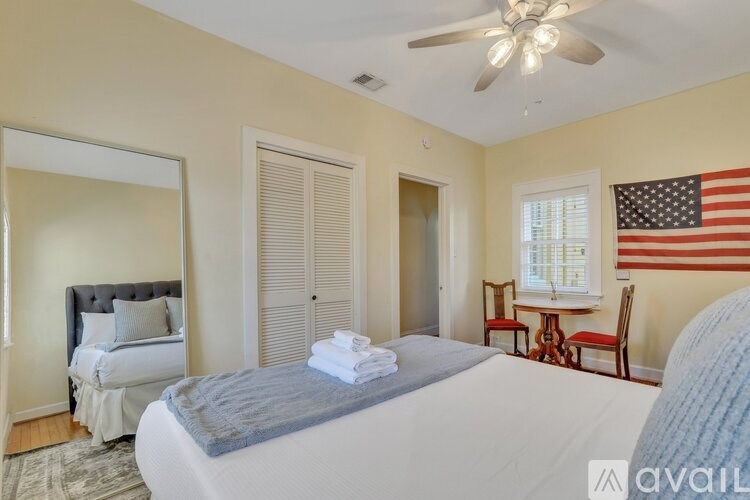 A bedroom with a bed, a chair, and an American flag on the wall.