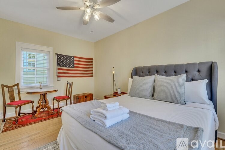 A bedroom with a bed, chair, and American flag on the wall.