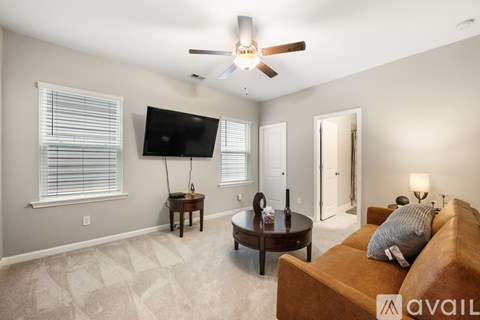 A living room with a brown couch and a flat screen TV mounted on the wall.