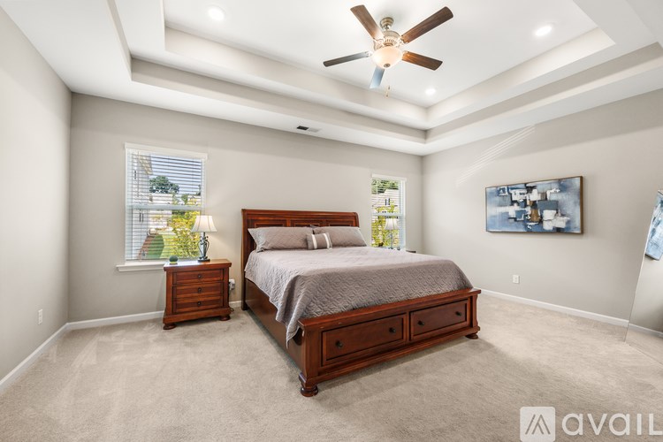A bedroom with a bed, dresser, and ceiling fan.