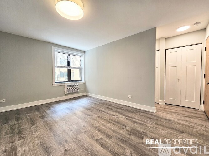 A room with wooden flooring and a window with blinds.
