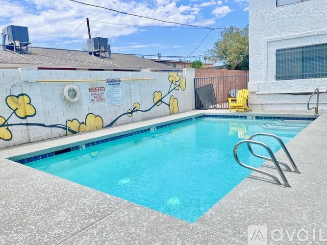 A pool with a yellow chair and a wall with yellow flowers.