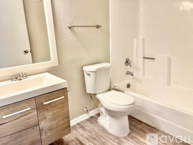 A white toilet is in a bathroom with a sink and a bathtub.