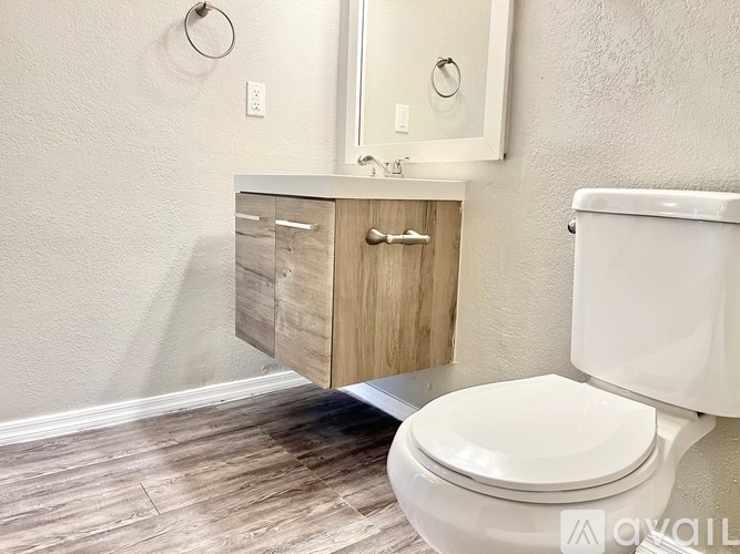 A white toilet sits next to a wooden cabinet in a bathroom.
