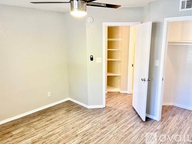 A room with a ceiling fan and a doorway leading to another room.