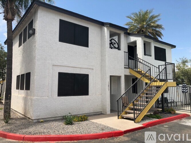A white house with a black railing and a yellow staircase.