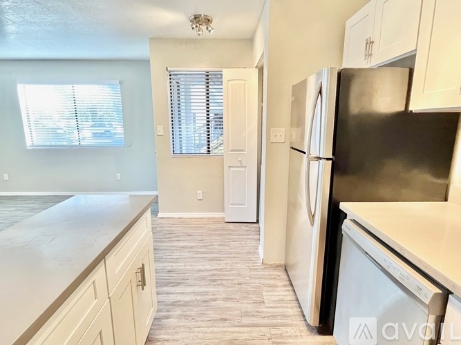 A kitchen with a refrigerator and a window with blinds.