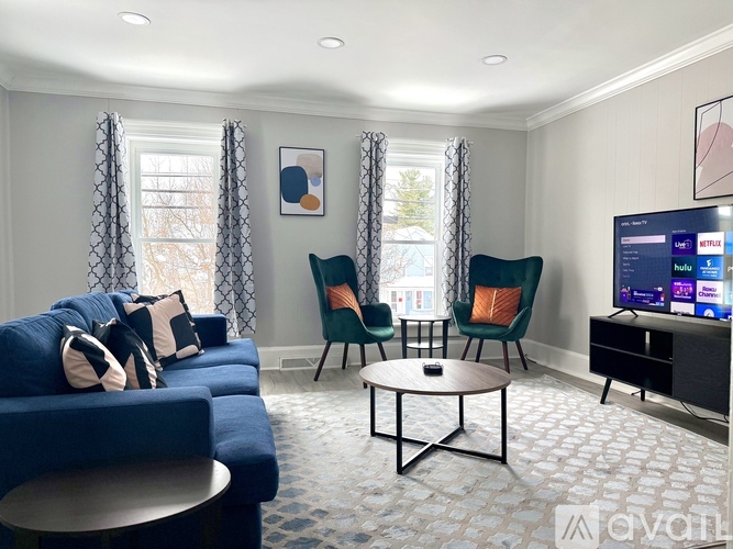 A living room with a blue sofa, two chairs, and a television.