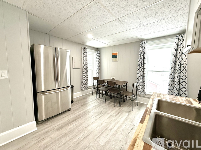 A kitchen with a stainless steel refrigerator and a dining table with chairs.