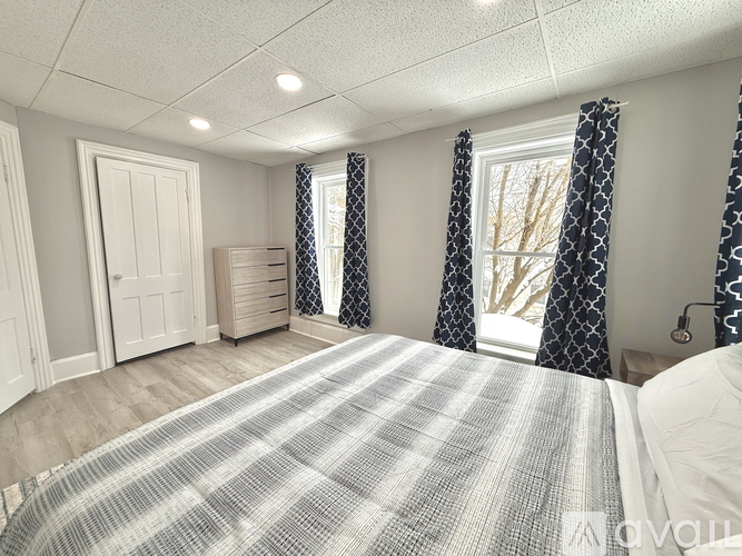 A bedroom with a large bed and a window with curtains.