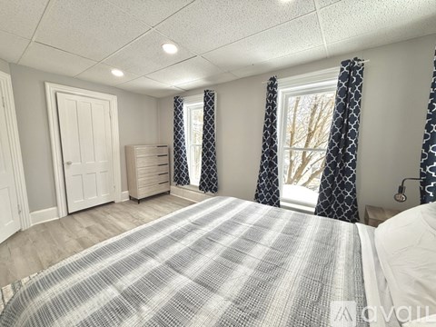 A bedroom with a large bed and a window with curtains.