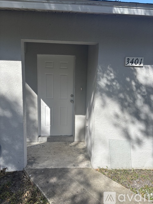 A white door is on the left side of a building with the number 3401 on the right side.