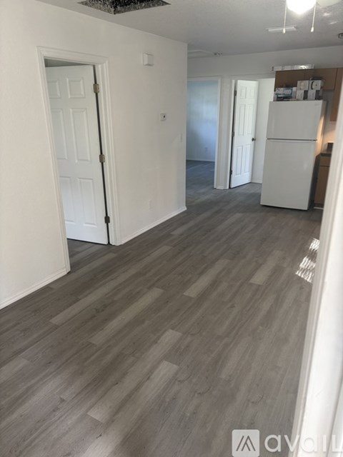 A room with a white door and a white fridge.