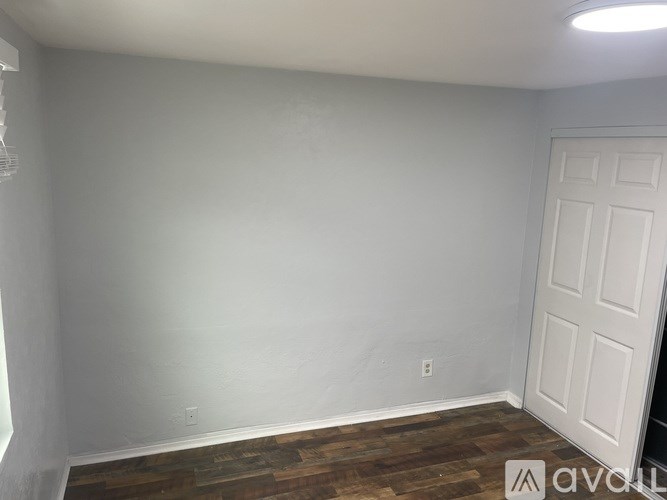 A room with a white door and wooden flooring.