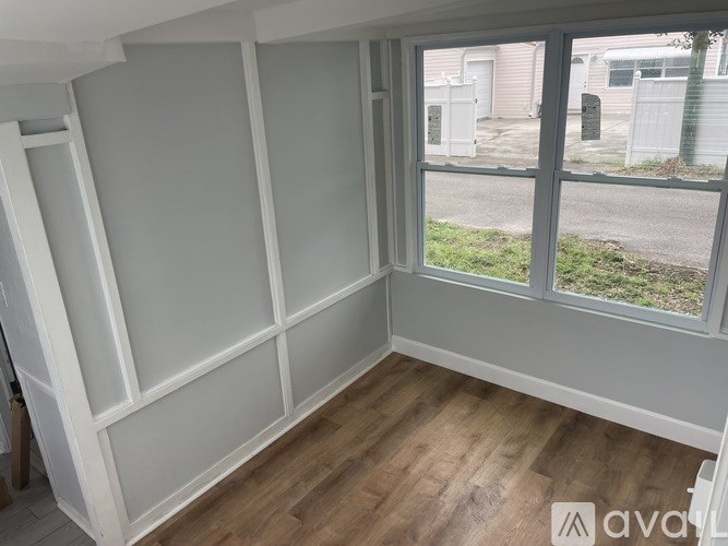 A room with a large window and wooden flooring.