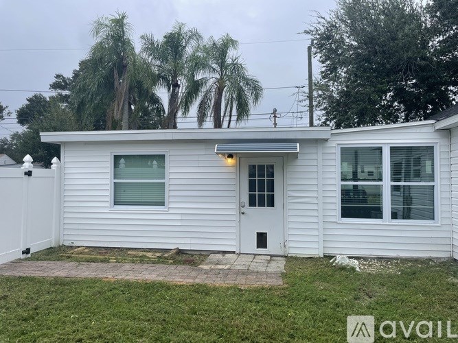 A white house with a grey roof and a white fence.