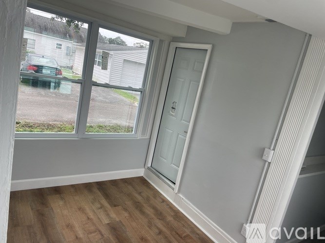 A room with a white door and a window overlooking a yard.