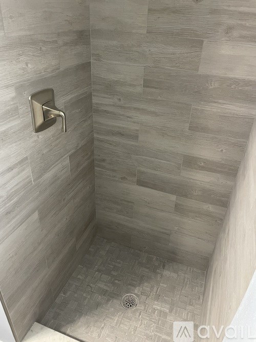 A shower with a silver faucet and a tiled floor.