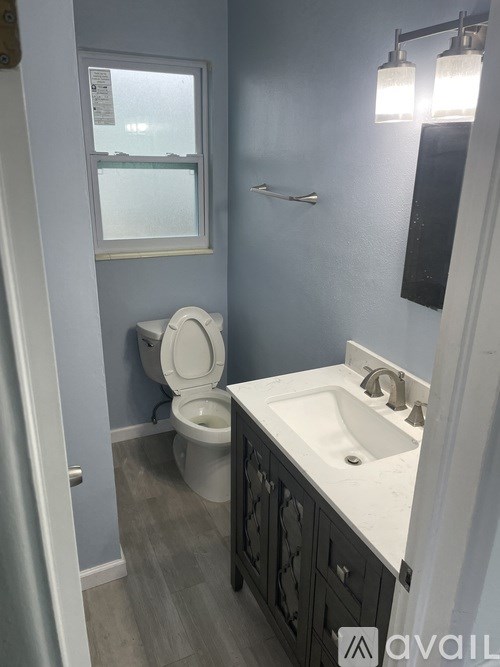A bathroom with a toilet, sink, and mirror.