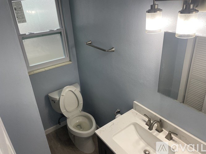 A bathroom with a toilet, sink, and mirror.