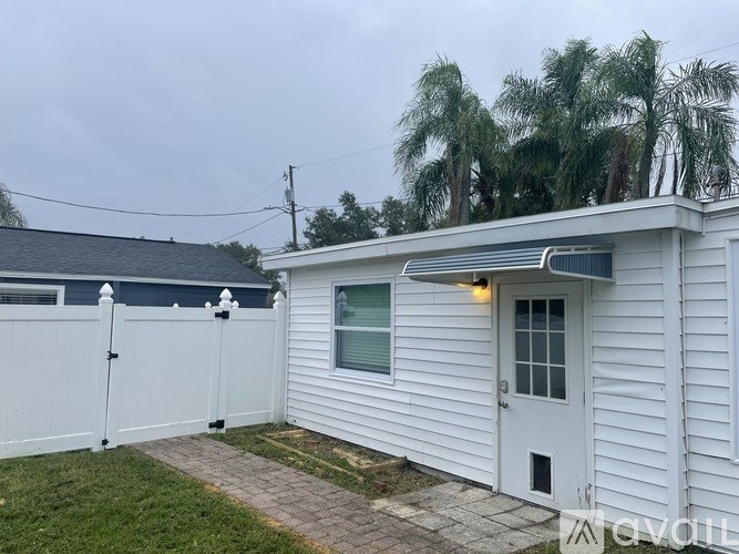A white house with a grey roof and a white fence.