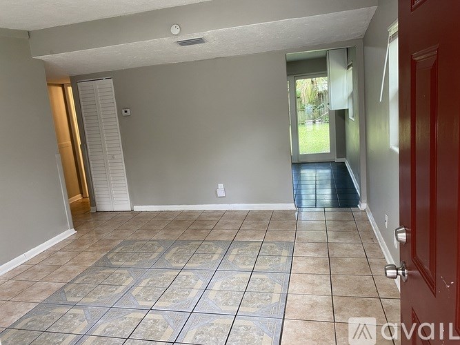 A room with a tiled floor and a red door.
