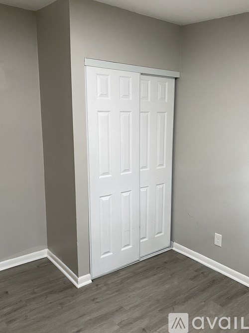 A white door in a room with grey walls and wooden flooring.