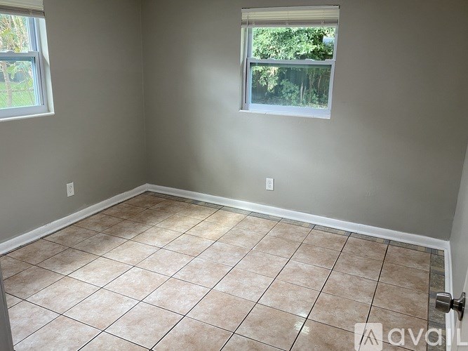 A room with beige tiled flooring and a window.