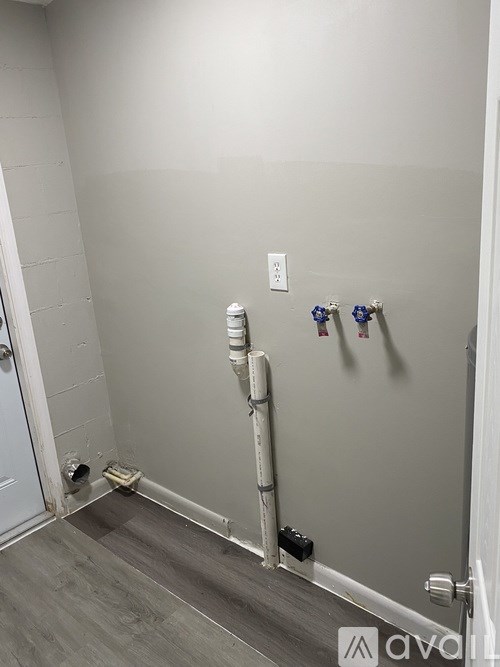 A bathroom with a white door and a white pipe running along the wall.