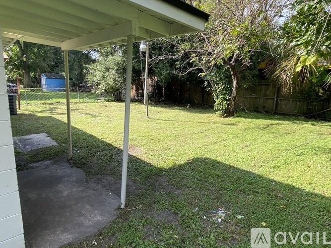 A backyard with a white fence and a tree.