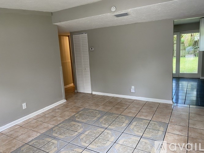 A room with tile flooring and a doorway leading to another room.
