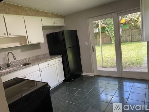 A kitchen with a black refrigerator and white cabinets.
