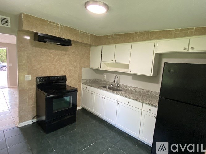 A kitchen with black appliances and white cabinets.