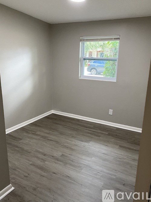 A room with a window and a view of a blue car outside.