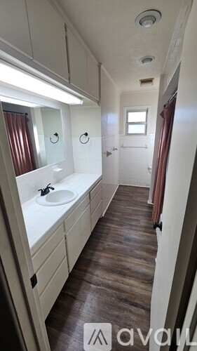 A bathroom with a sink, mirror, and wooden floor.