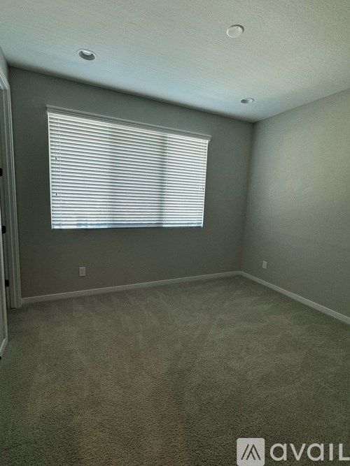 A room with a carpeted floor and a window with blinds.