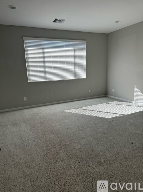 A room with a carpeted floor and a window with blinds.