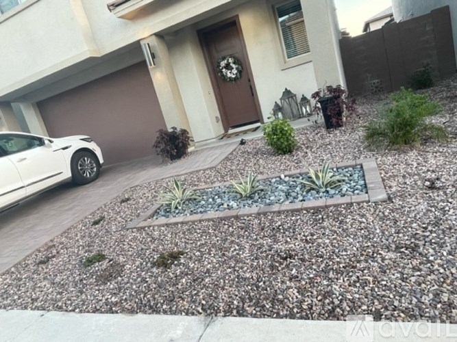 A white car is parked in front of a house with a brown door.