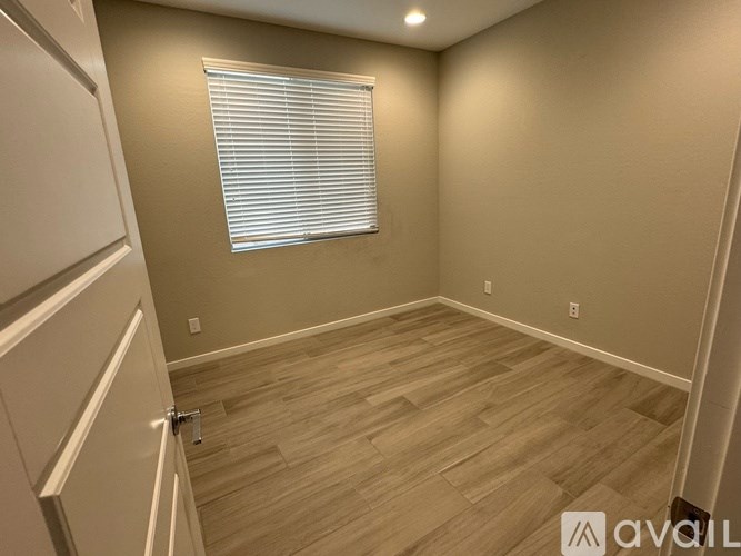 A room with wooden flooring and a window with blinds.