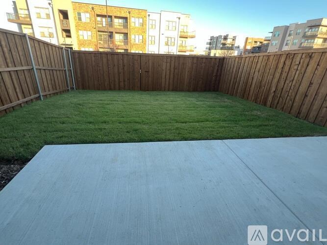 A backyard with a wooden fence and a concrete slab.