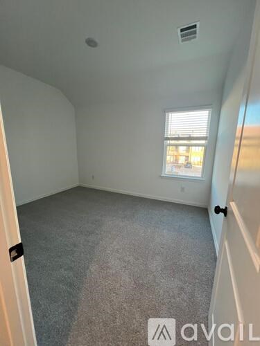 A room with a carpeted floor and a window with blinds.