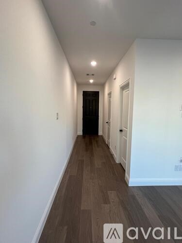 A long hallway with wood flooring and white walls.